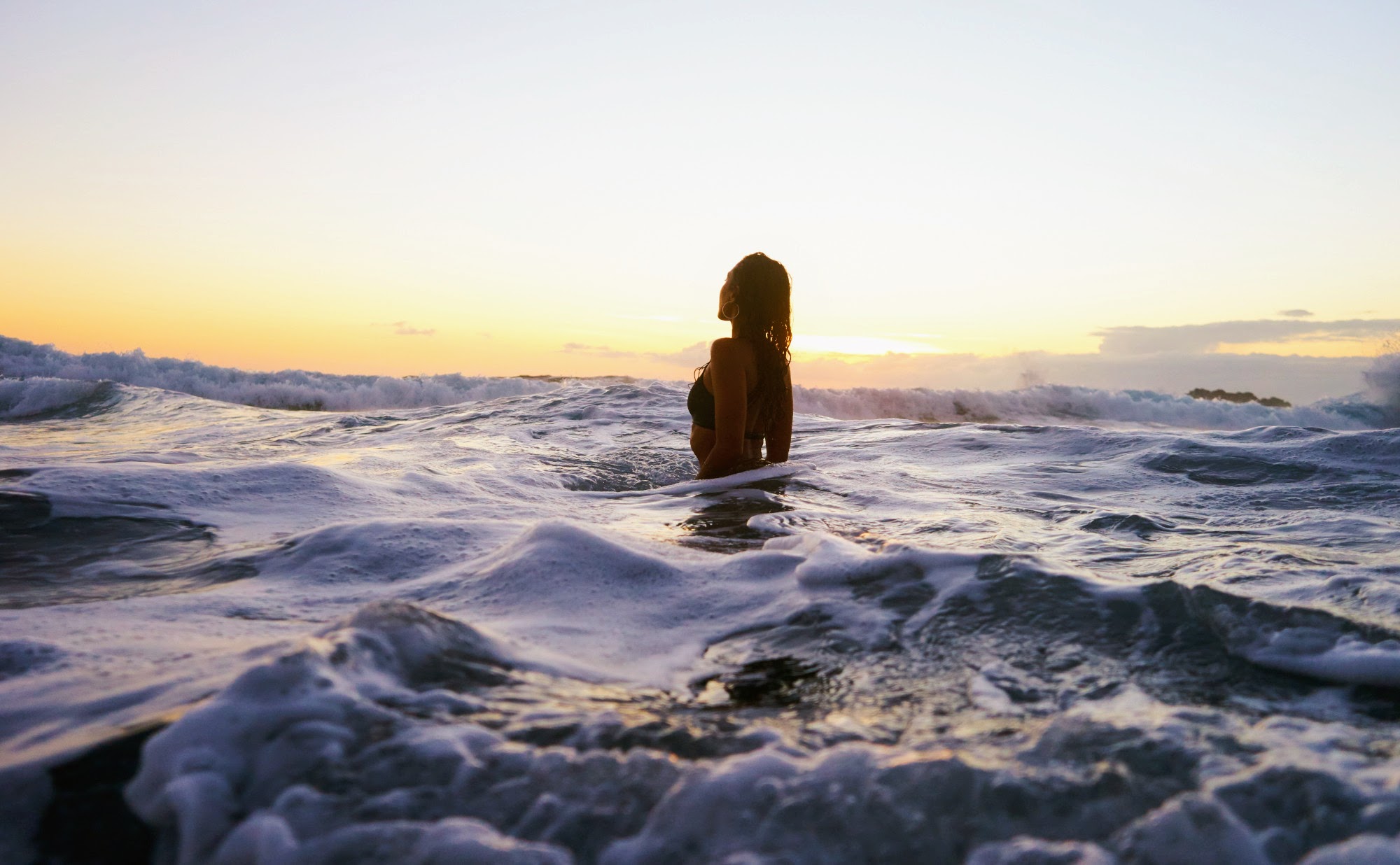 A person in the ocean at sunset.
