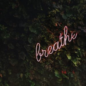 A neon sign that says breathe on the side of a wall.
